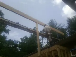 Carpenter setting a ridge beam over a new addition frame — Ice Dam Removal by Roofing Brothers in Waukon