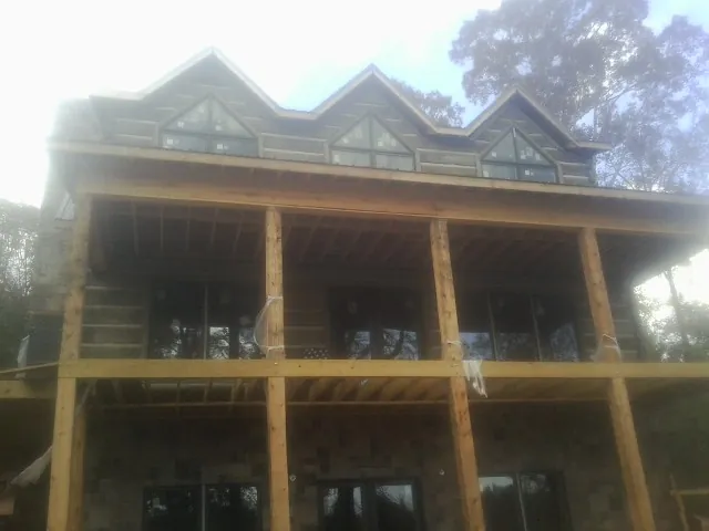 Dormers and porch framing on a large log home under construction — Roof Coating work by our crew in Waukon
