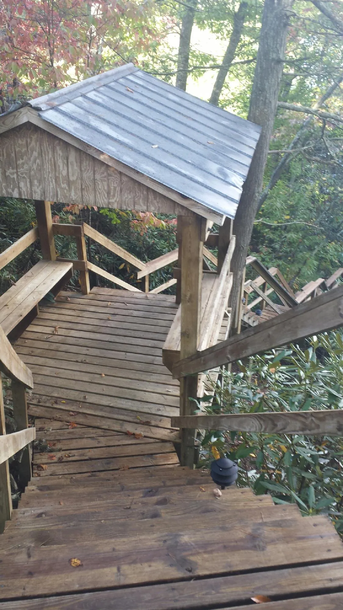 Metal roofed shelter over wooden steps on a wooded walkway — Skylight Repair & Installation work by our crew in Waukon