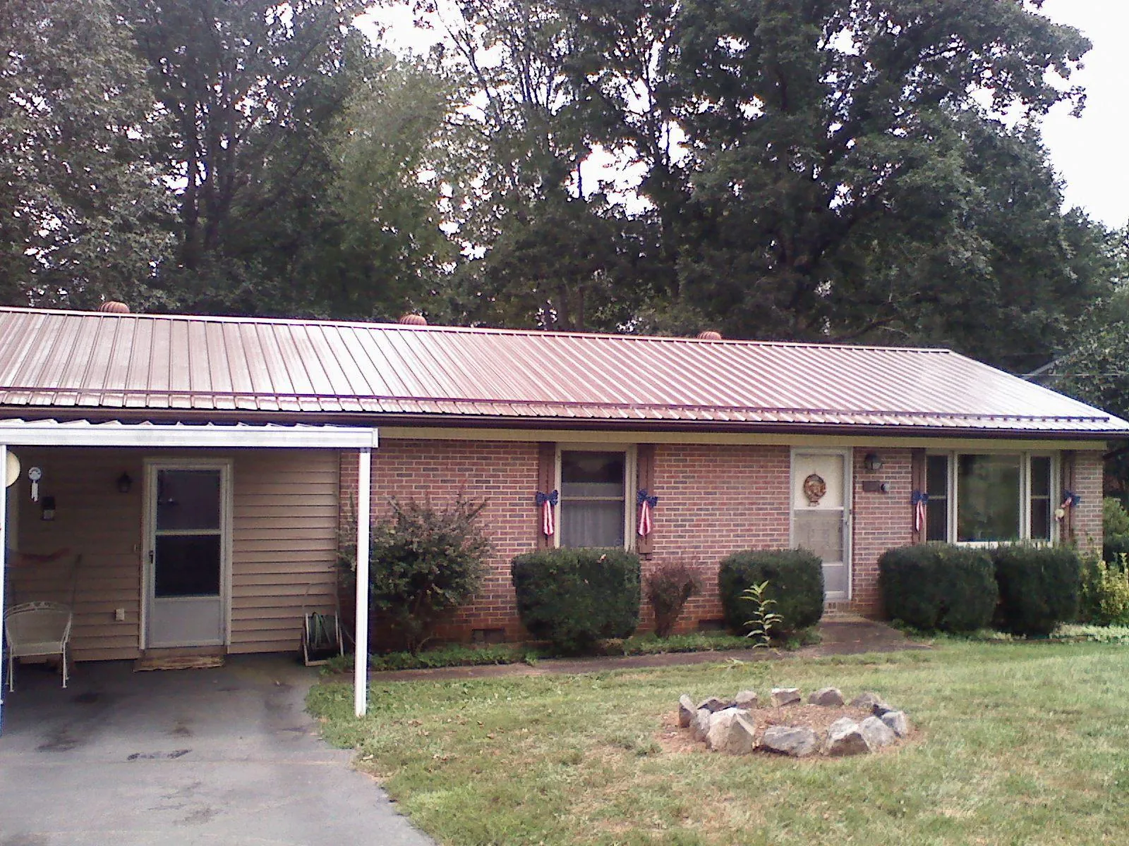 Bronze metal roof and carport on a brick ranch home — Roof Repair work by our crew in Waukon