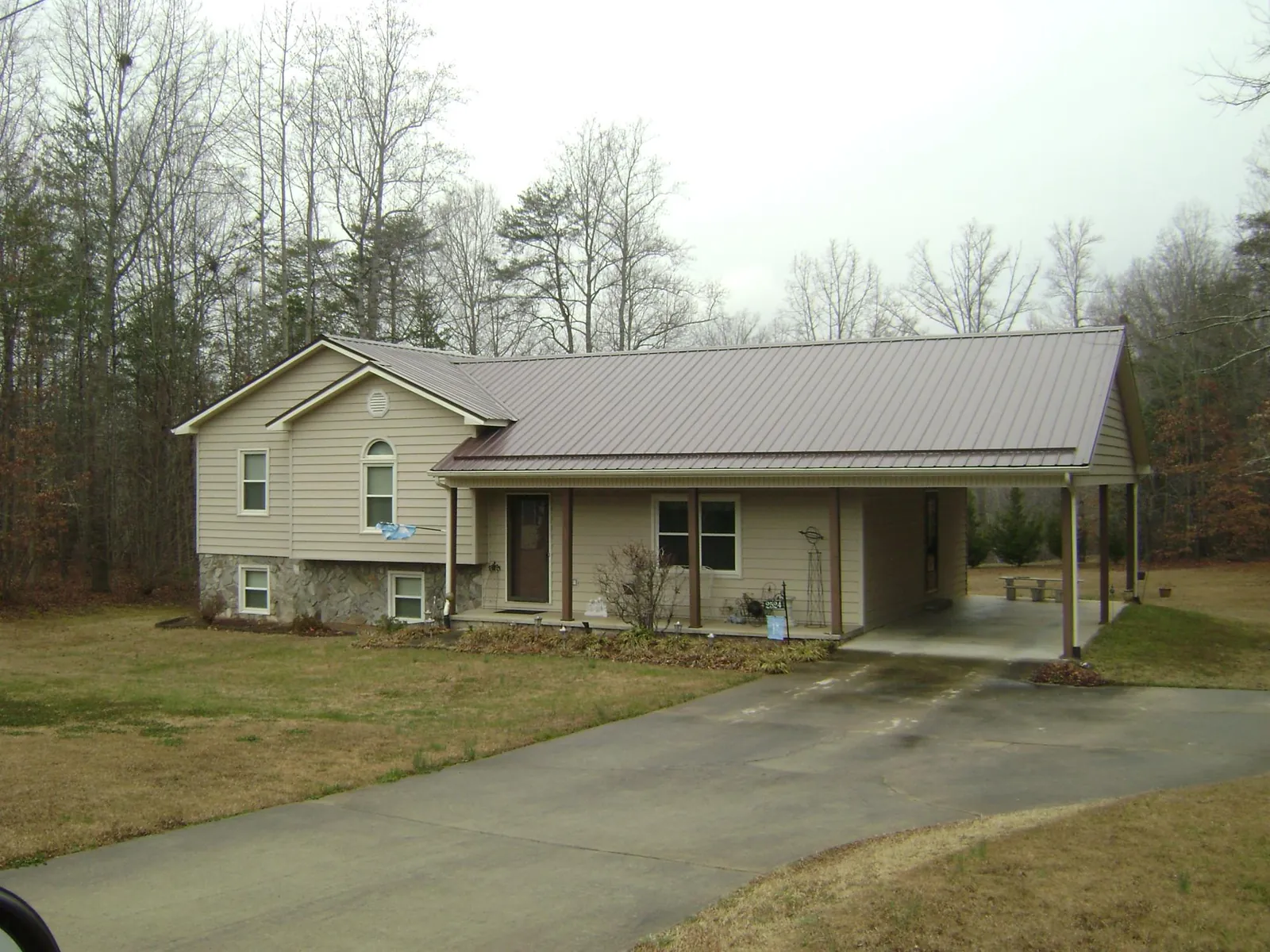 Brown metal roof on a tan split level home with an attached carport in Waukon