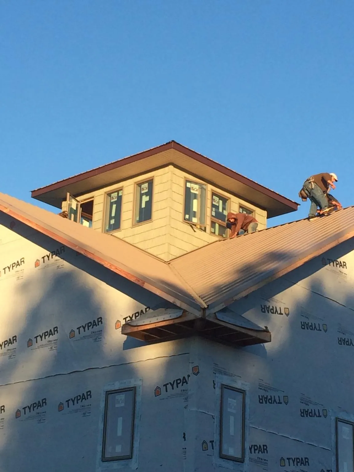 Roofers working around a rooftop cupola on a new metal roof at sunset — Roof Waterproofing in Waukon by Roofing Brothers